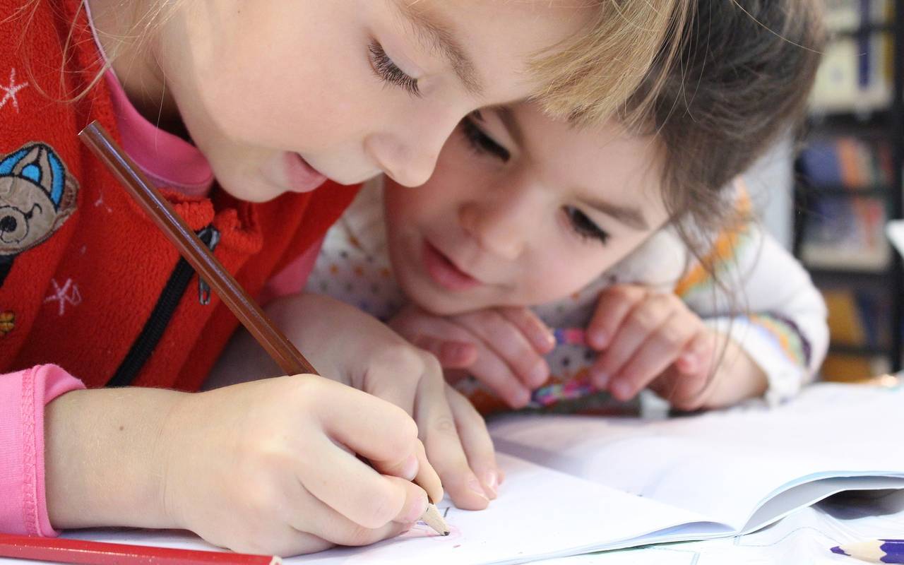 Grundschulkinder schreiben in einem Heft