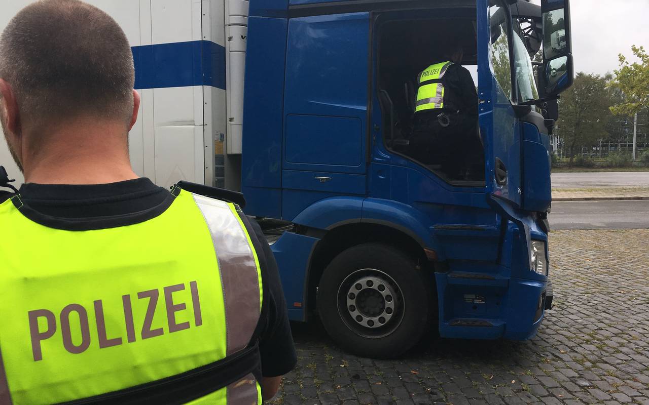 Polizisten kontrollieren einen LKW und nehmen das Führerhaus in Augenschein.