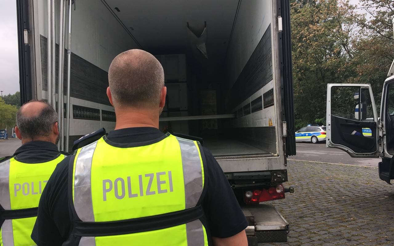 Zwei Polizeibeamten kontrollieren die Ladefläche eines LKWs.