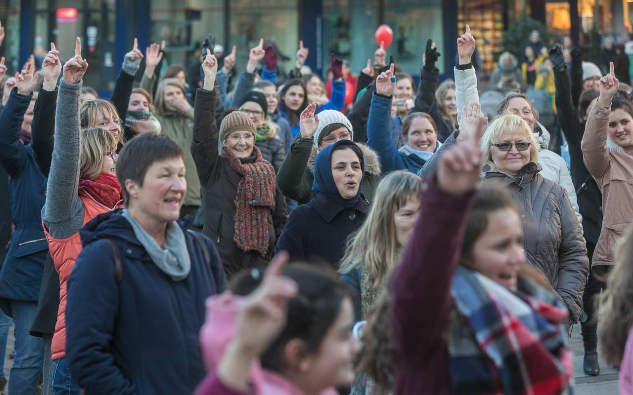 Frauen stehen auf einem Platz und recken gleichzeitig eine Hand in die Luft