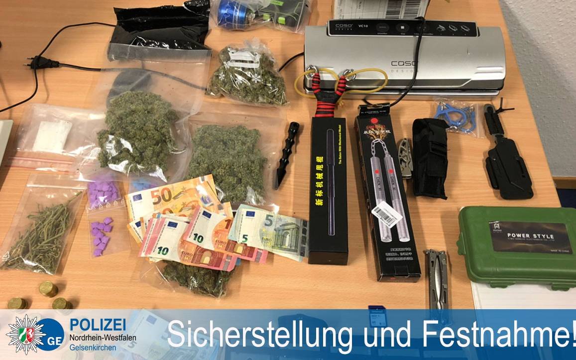 Auf einem Schreibtisch sind Tüten mit Drogen, Bargeld und Waffen ausgebreitet.