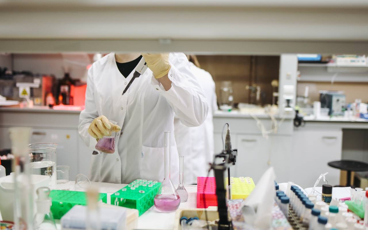 Eine Forscherin in ihrem Labor mit Becherglas und Pipette.