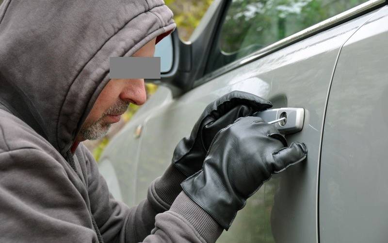 Ein Autodieb mit Kapuze in Aktion