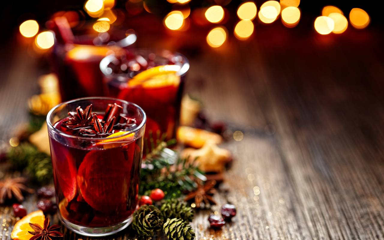 Glühwein steht dekorativ angerichtet auf einer Holzplatte.