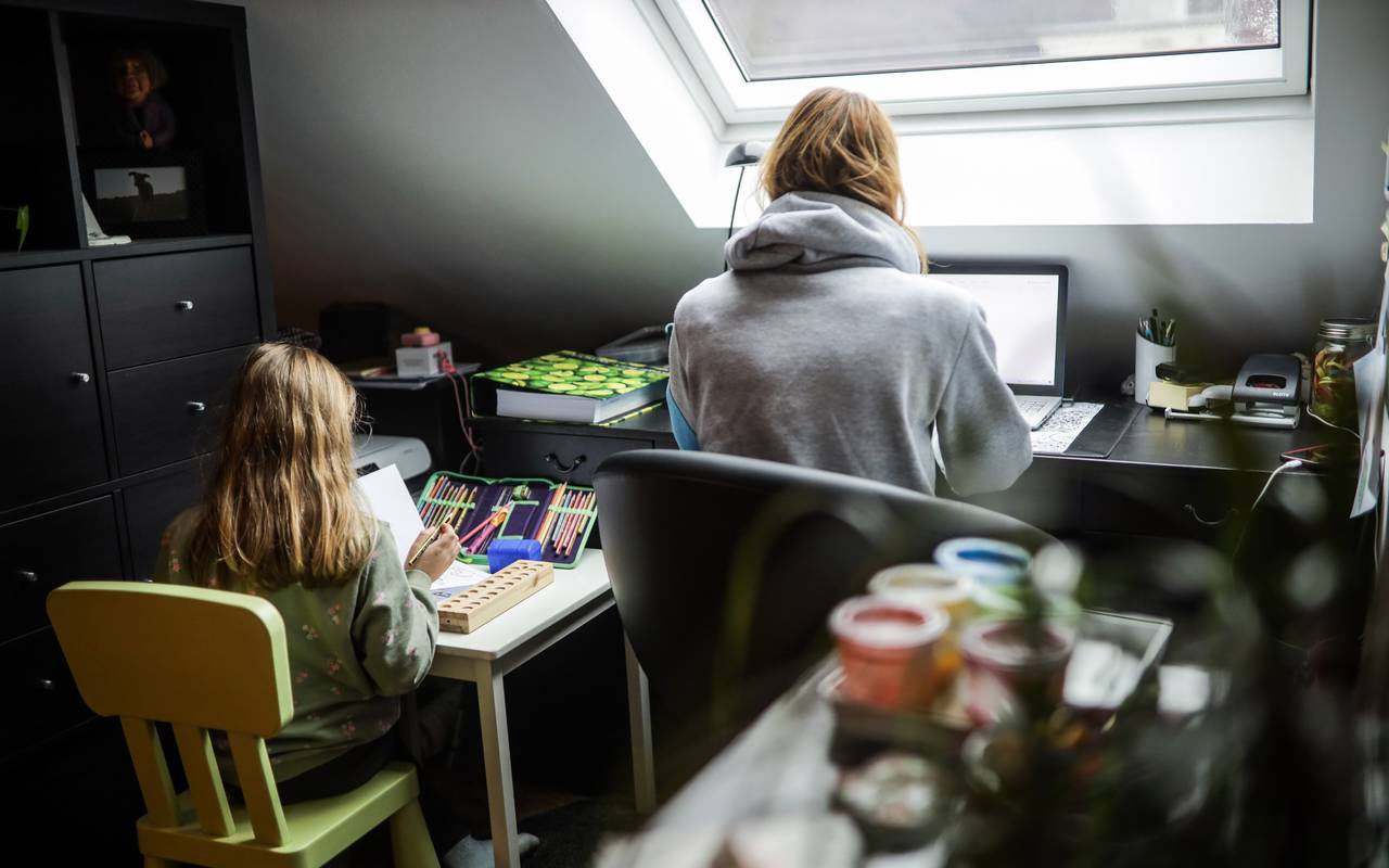 Eine Mutter im Homeoffice, die Tochter sitzt daneben
