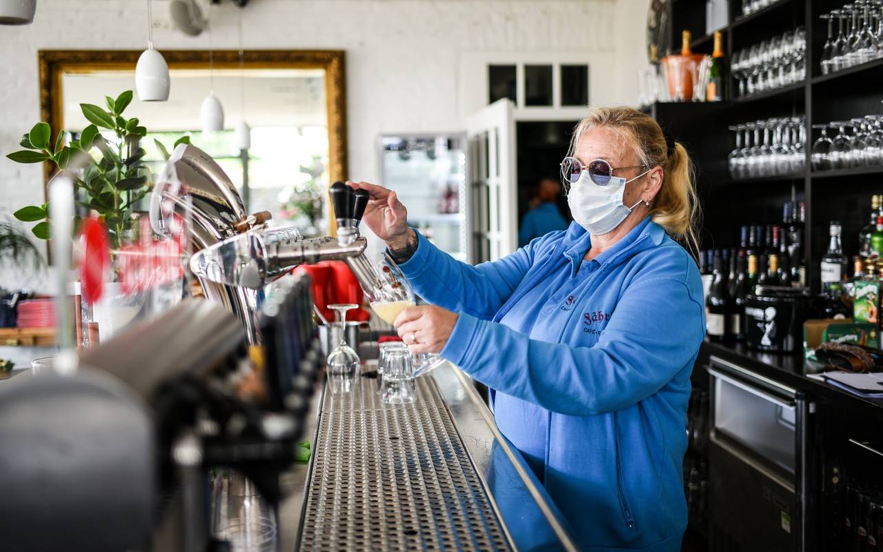 Gastwirtin zapft Bier mit Maske