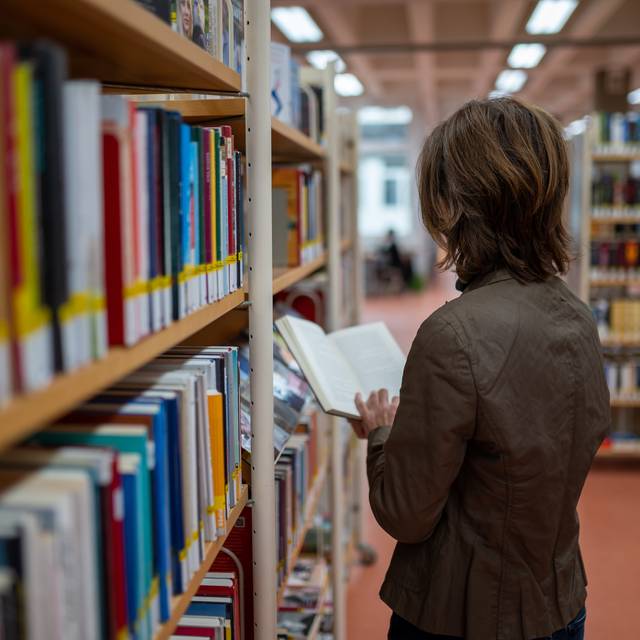 Eine Frau steht an einem Bücherregal