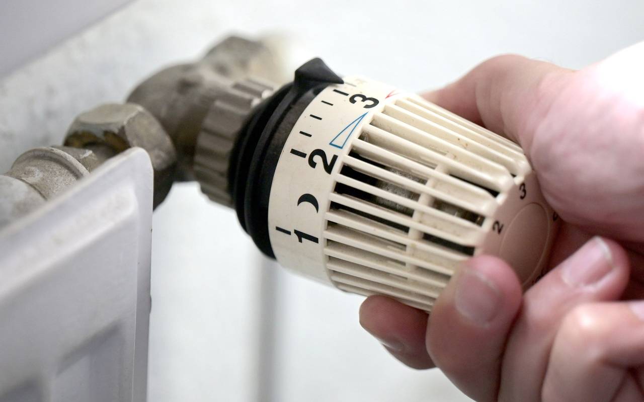 Ein Thermostat an der Heizung wird runter gedreht