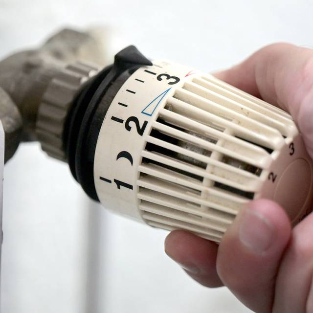 Ein Thermostat an der Heizung wird runter gedreht