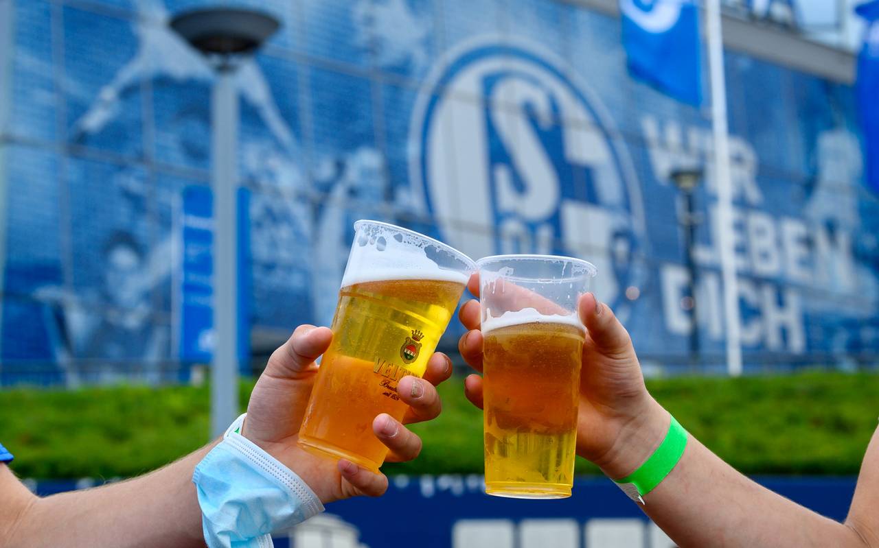 Zwei Schalke-Fans stoßen vor der Veltins-Arena mit Bierbechern aus Plastik an