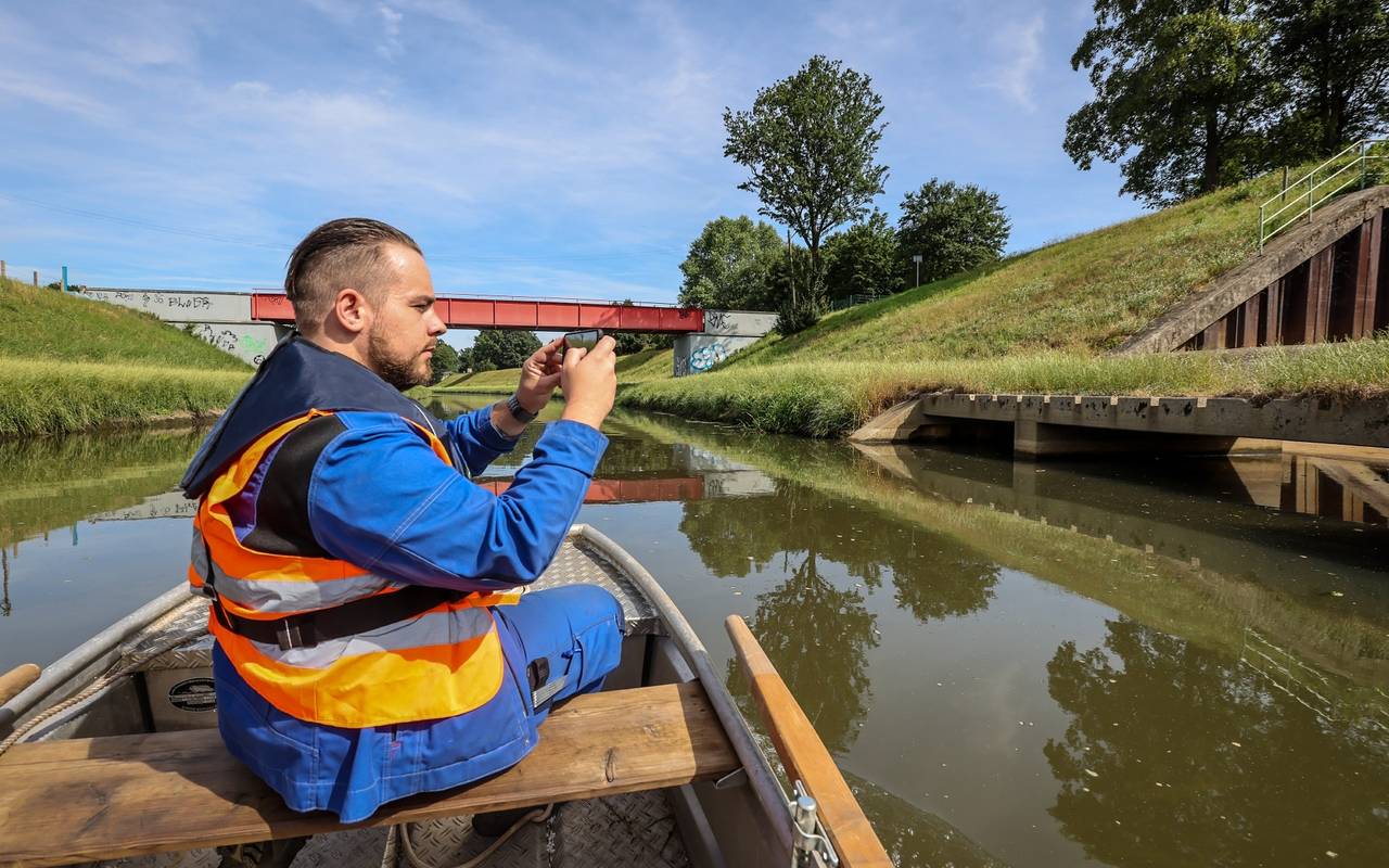 Ein Mitarbeiter der Emschergenossenschaft fährt in einem Boot auf der Emscher und macht Fotos