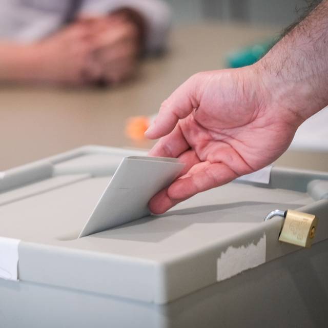 Wahlzettel wird in eine Wahlurne geworfen