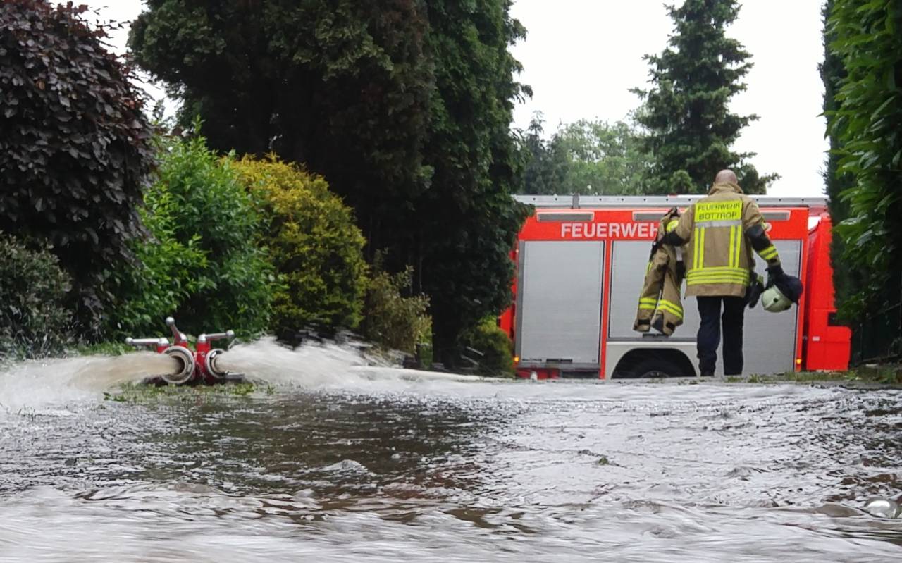 Ein Feuerwehrmann steht auf einer überfluteten Straße