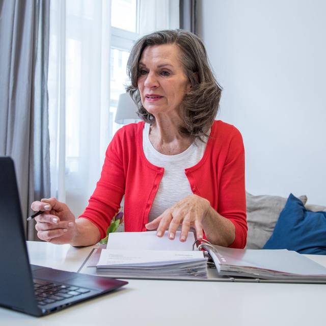 Eine ältere Frau arbeitet am Laptop.