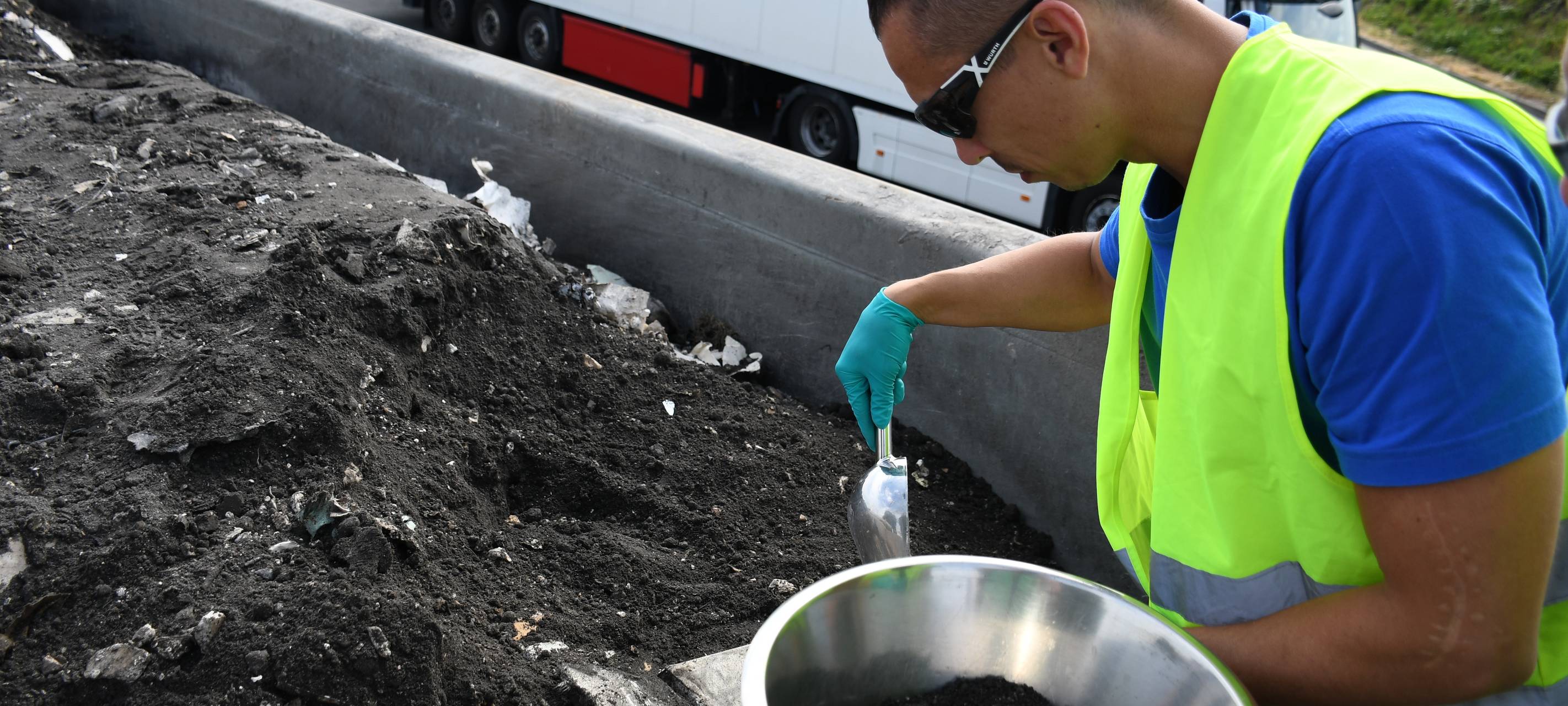 Ein Mitarbeiter des LANUV entnimmt eine Probe aus einer LKW-Ladung, die im Anschluss untersucht wird.