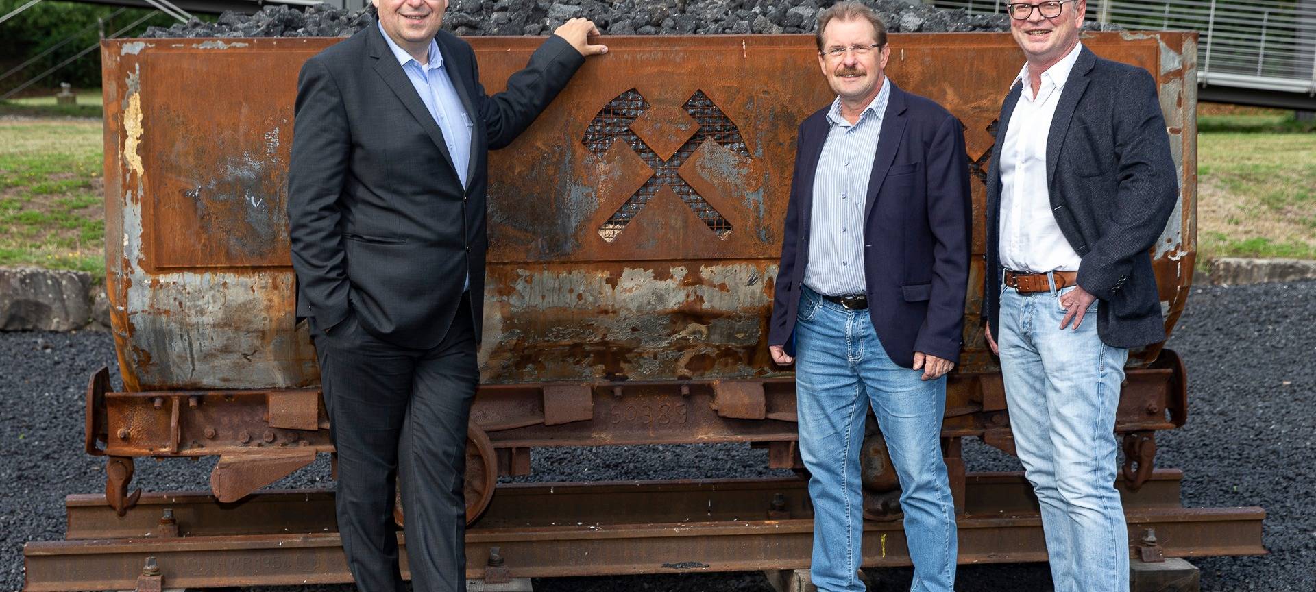 Eine Original-Lore aus dem Bergwerk steht im Nordsternpark. Davor Leute der Stadtmarketinggesellschaft, die sich über die Lore freuen.