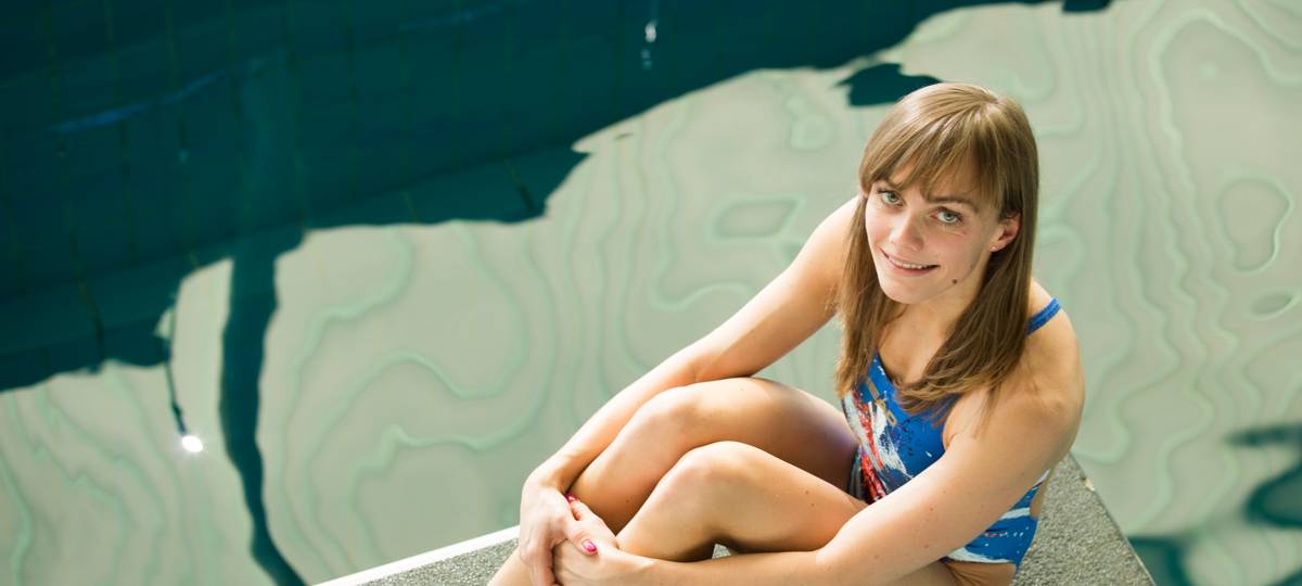 Jessica Steiger sitzt auf einem Sprungbrett über dem Wasser.