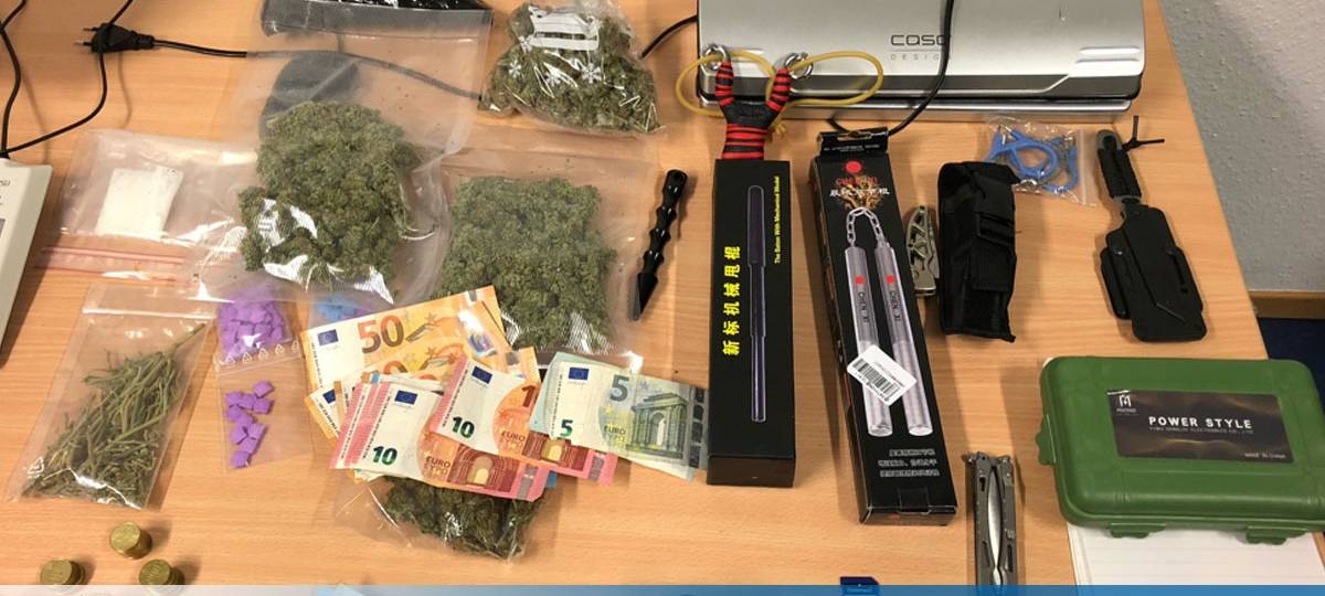 Auf einem Schreibtisch sind Tüten mit Drogen, Bargeld und Waffen ausgebreitet.