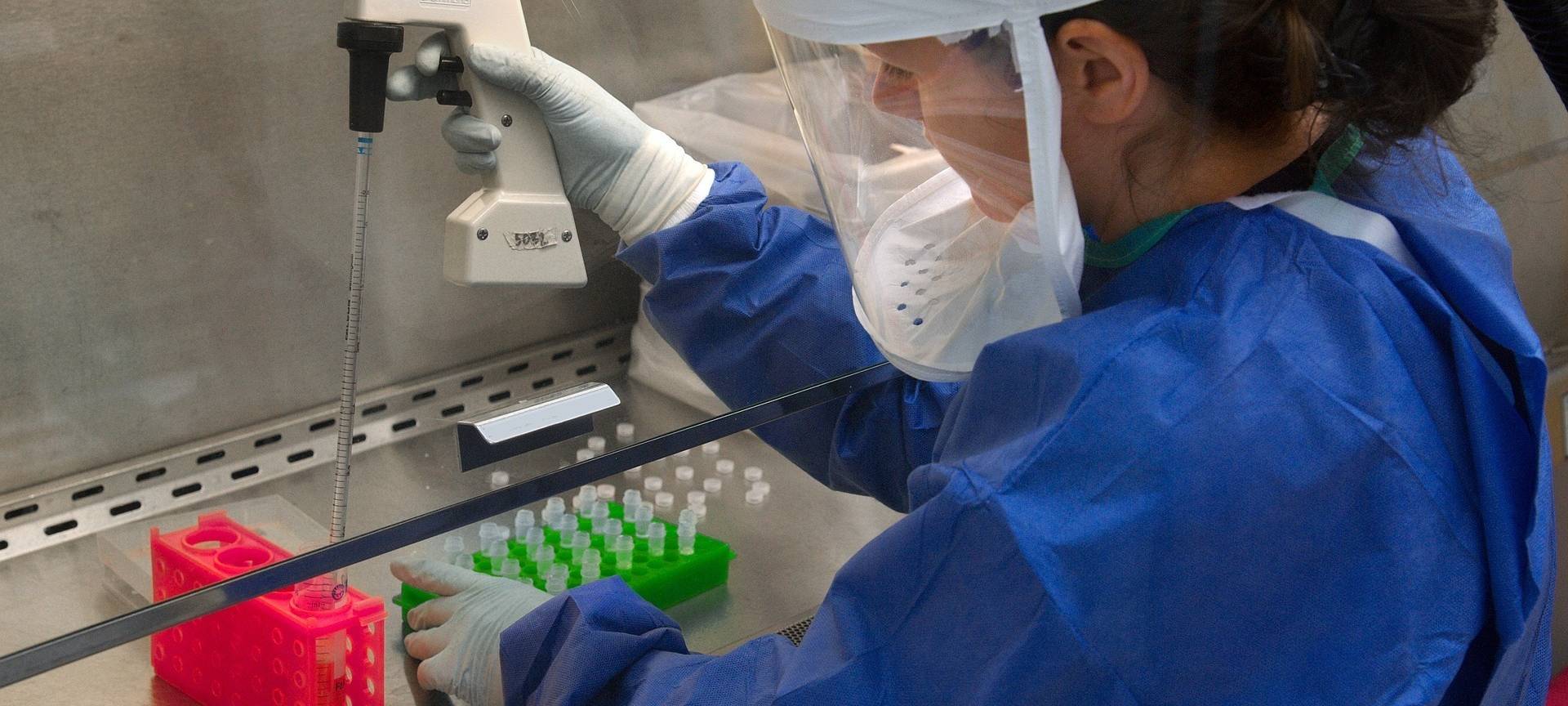 Eine Forscherin in ihrem Labor mit Schutzkleidung.