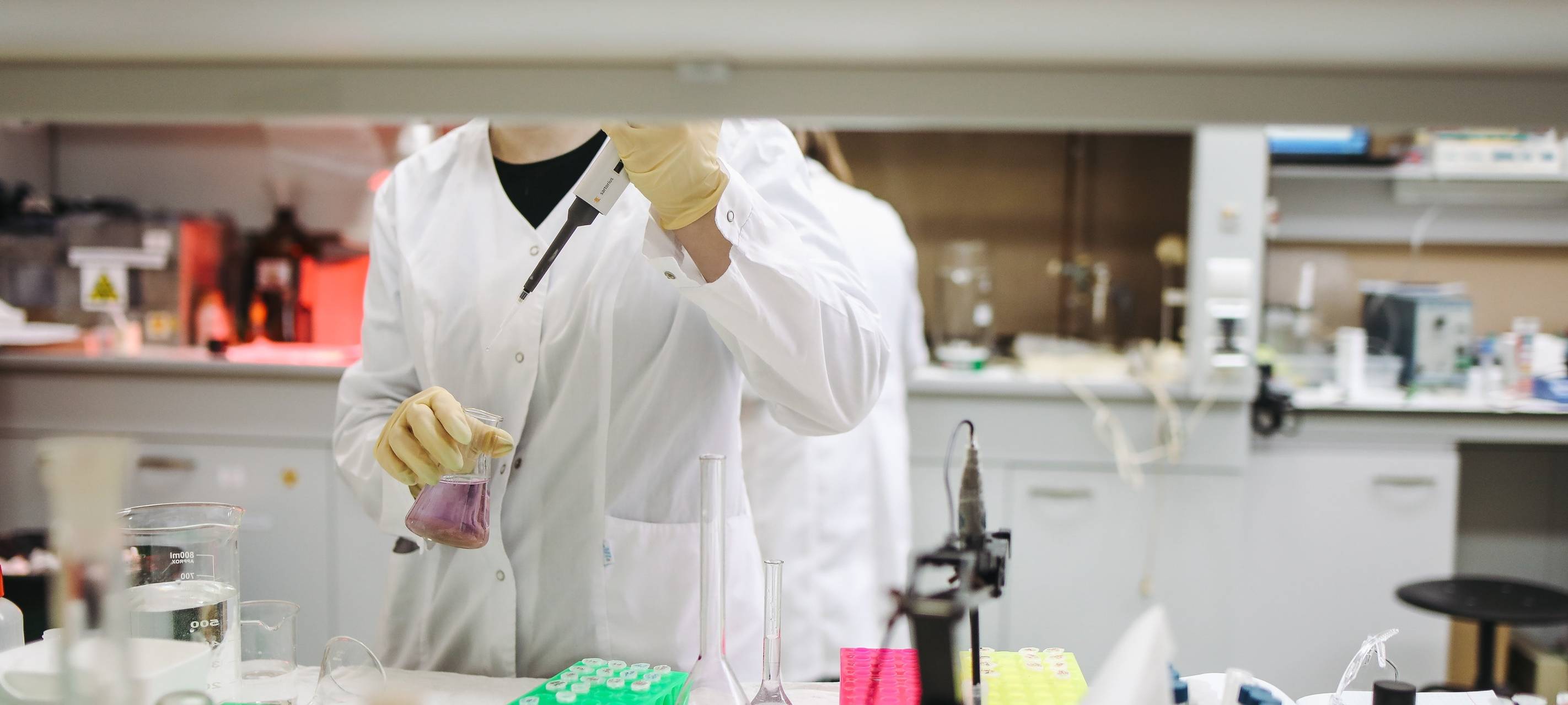 Eine Forscherin in ihrem Labor mit Becherglas und Pipette.