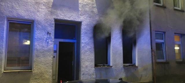 Dunkler Rauch dringt aus den Fenstern einer Erdgeschosswohnung