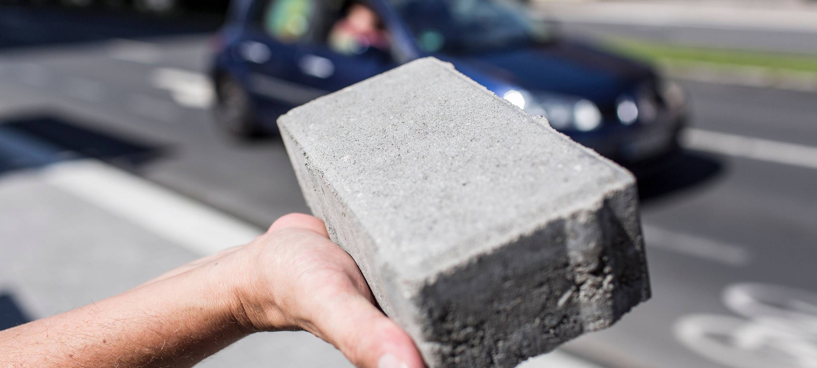 Ein Mann hält einen schadstoffschluckenden Pflasterstein in die Kamera