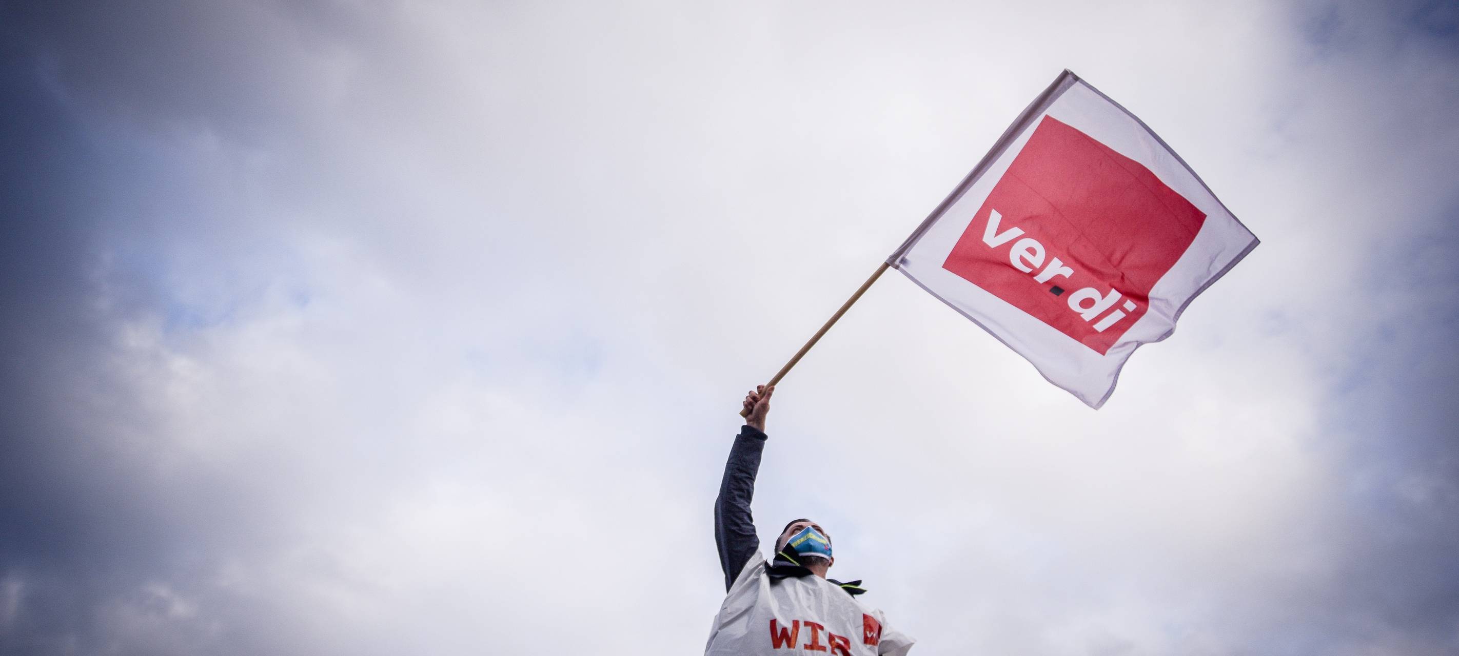 Ein Streikender schwenkt eine Verdi-Fahne