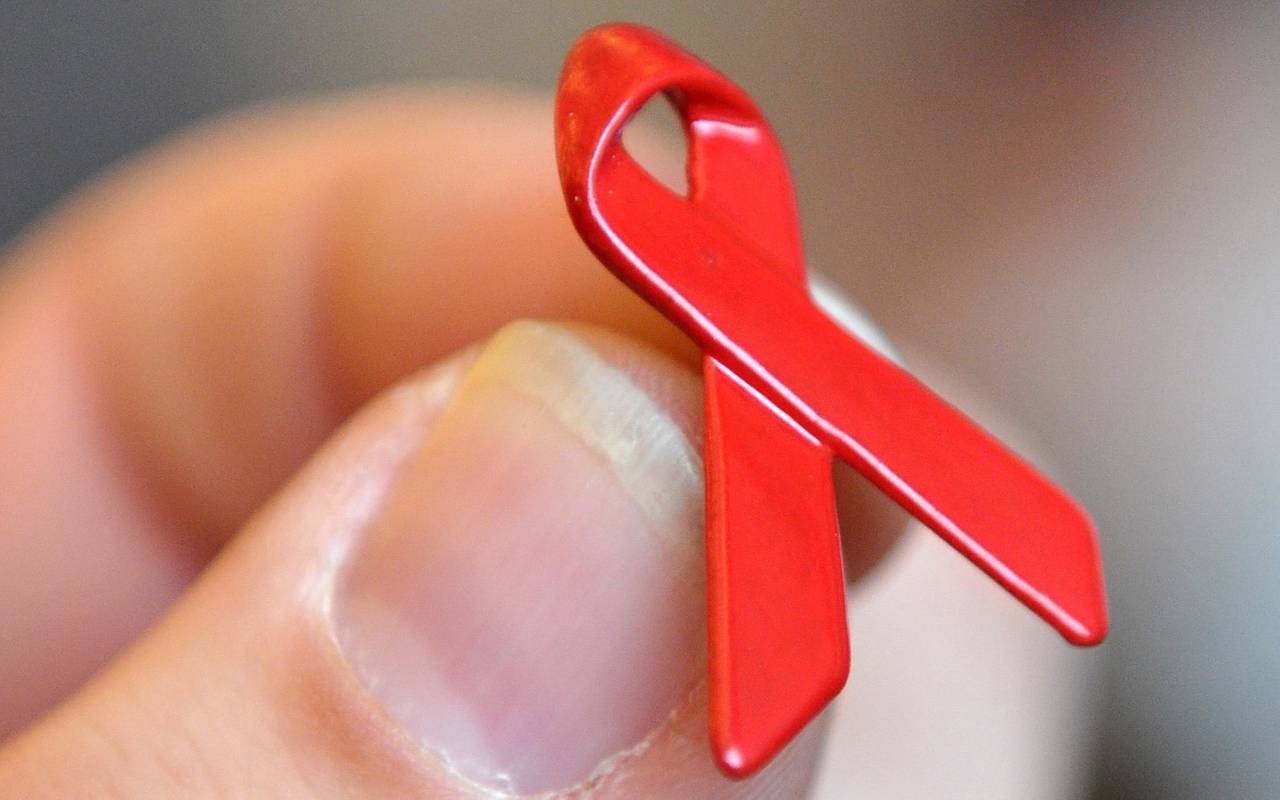 Eine Hand hält eine Aids-Schleife