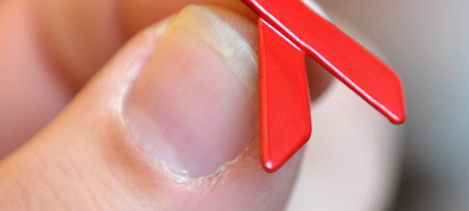 Eine Hand hält eine Aids-Schleife