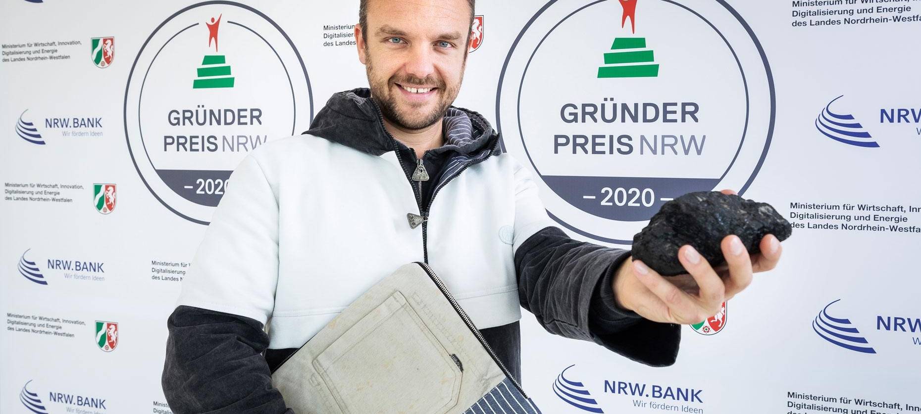 Grubenhelden-Chef Matthias Bohm vor einer Wand des Gründerpreises NRW