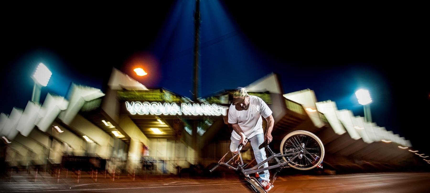 Ein BMX-Fahrer vor einem Stadion