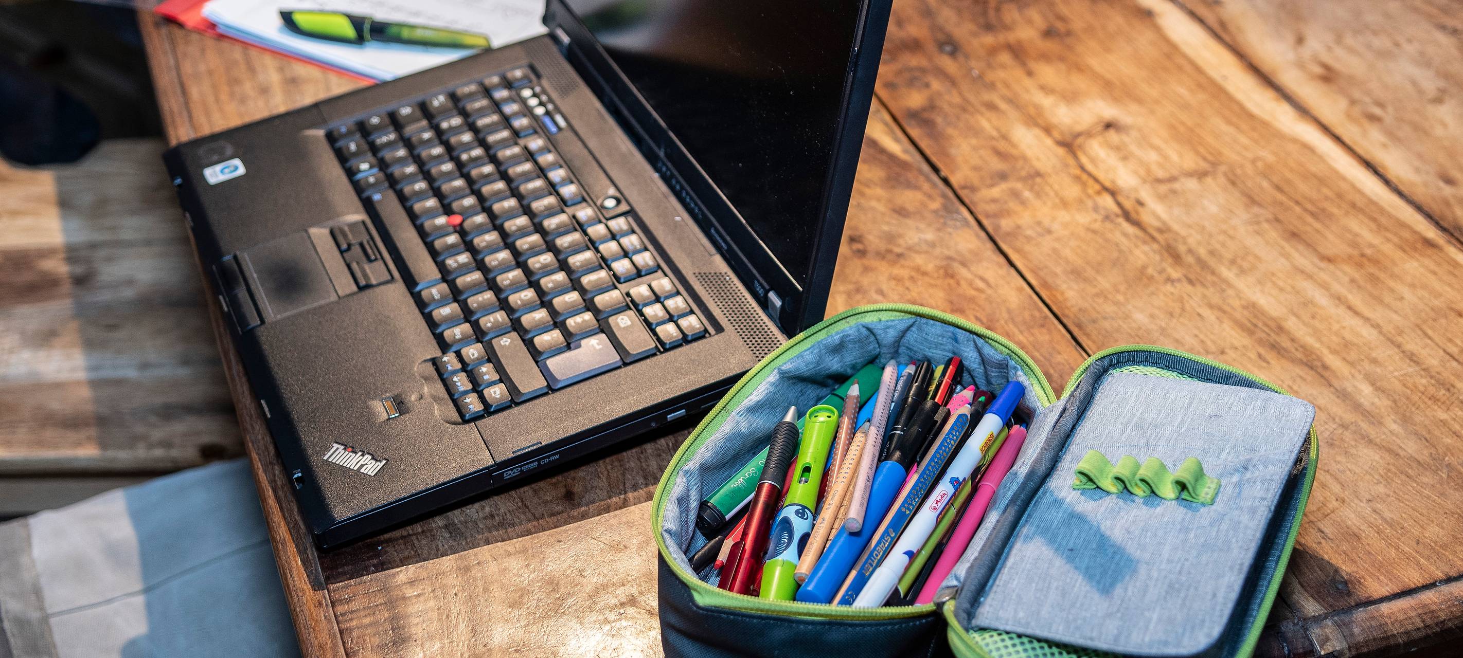 Laptop, Arbeitsblatt und Etui liegen auf einem Tisch