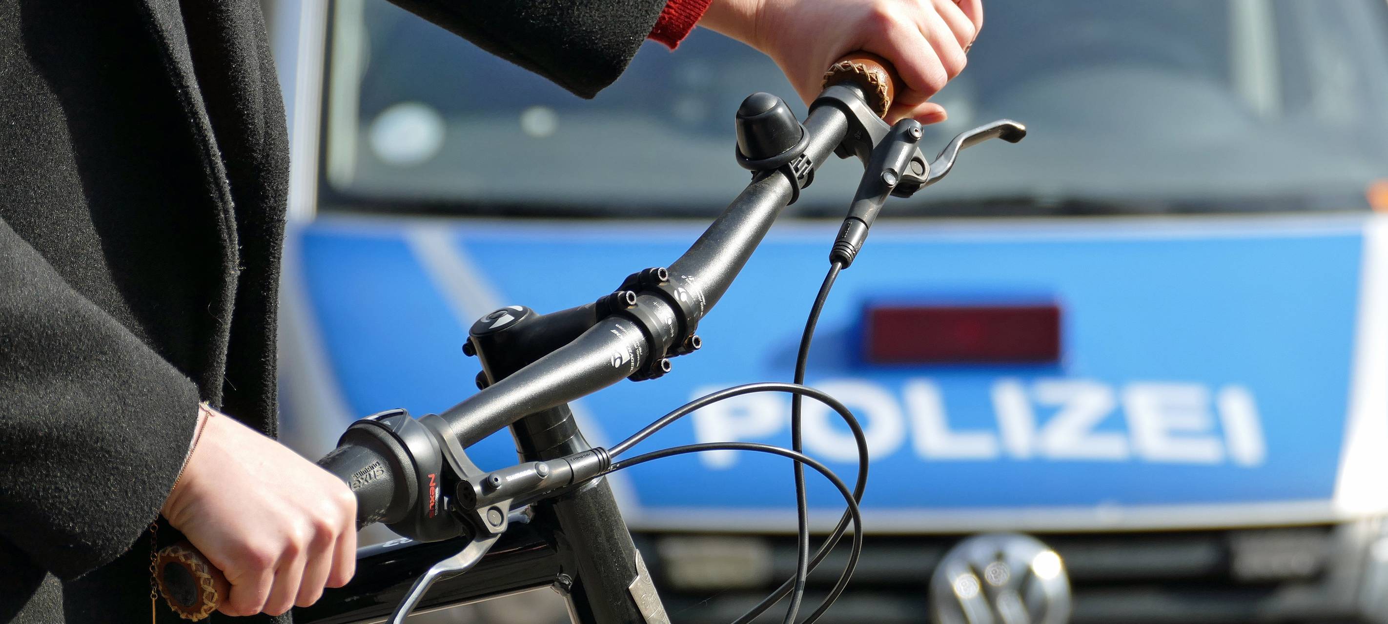 Ein Fahrradfahrer steht vor einem Polizeiauto