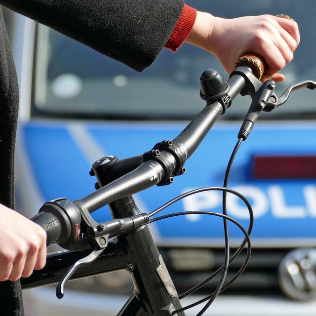 Ein Fahrradfahrer steht vor einem Polizeiauto