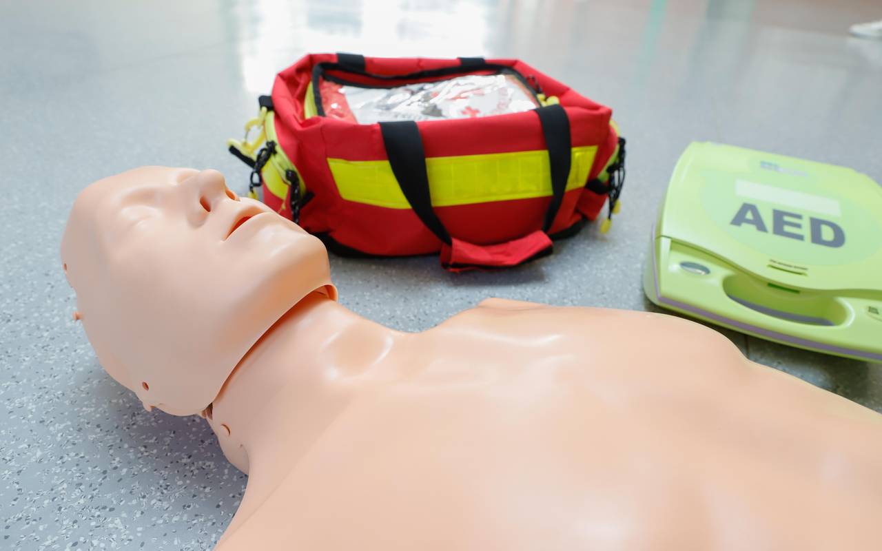Ein Erste-Hilfe-Dummy liegt neben einem Defibrilator