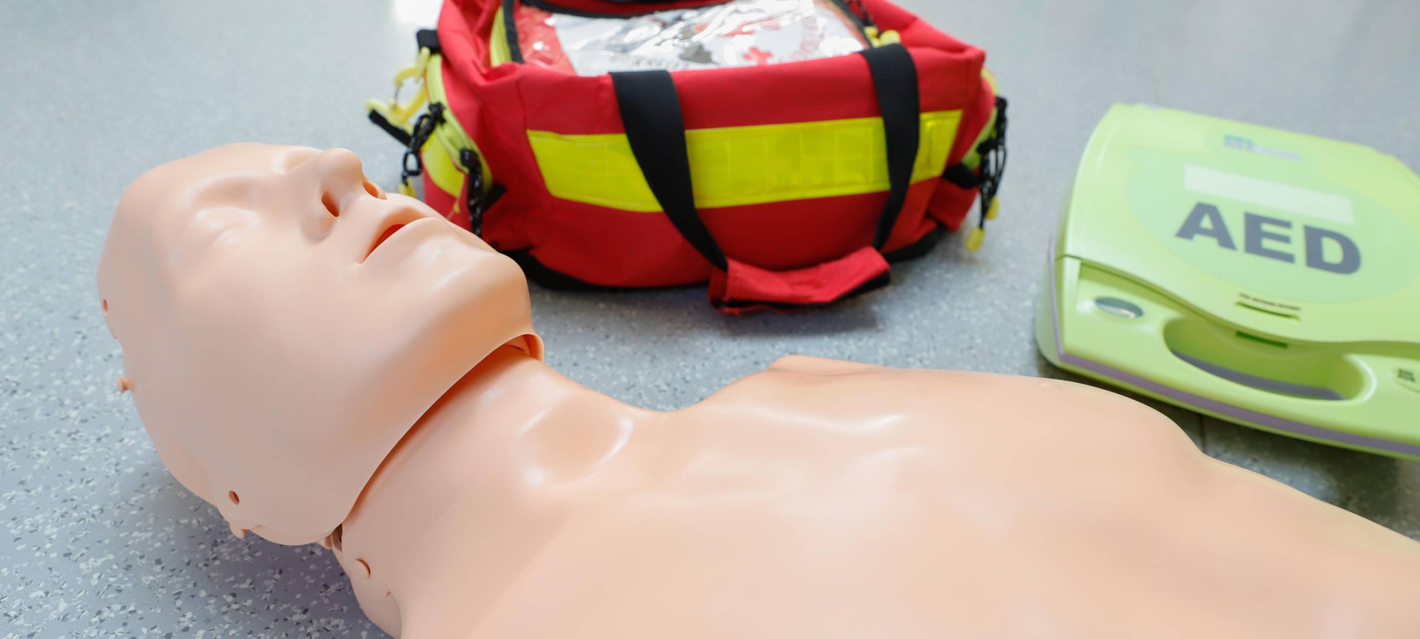 Ein Erste-Hilfe-Dummy liegt neben einem Defibrilator