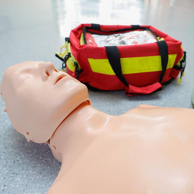 Ein Erste-Hilfe-Dummy liegt neben einem Defibrilator