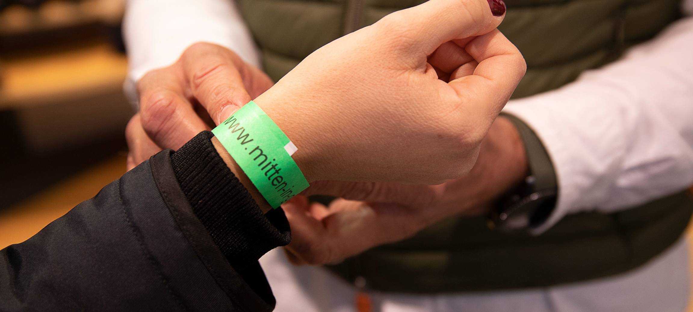 Arm mit einem grünen Papierbändchen