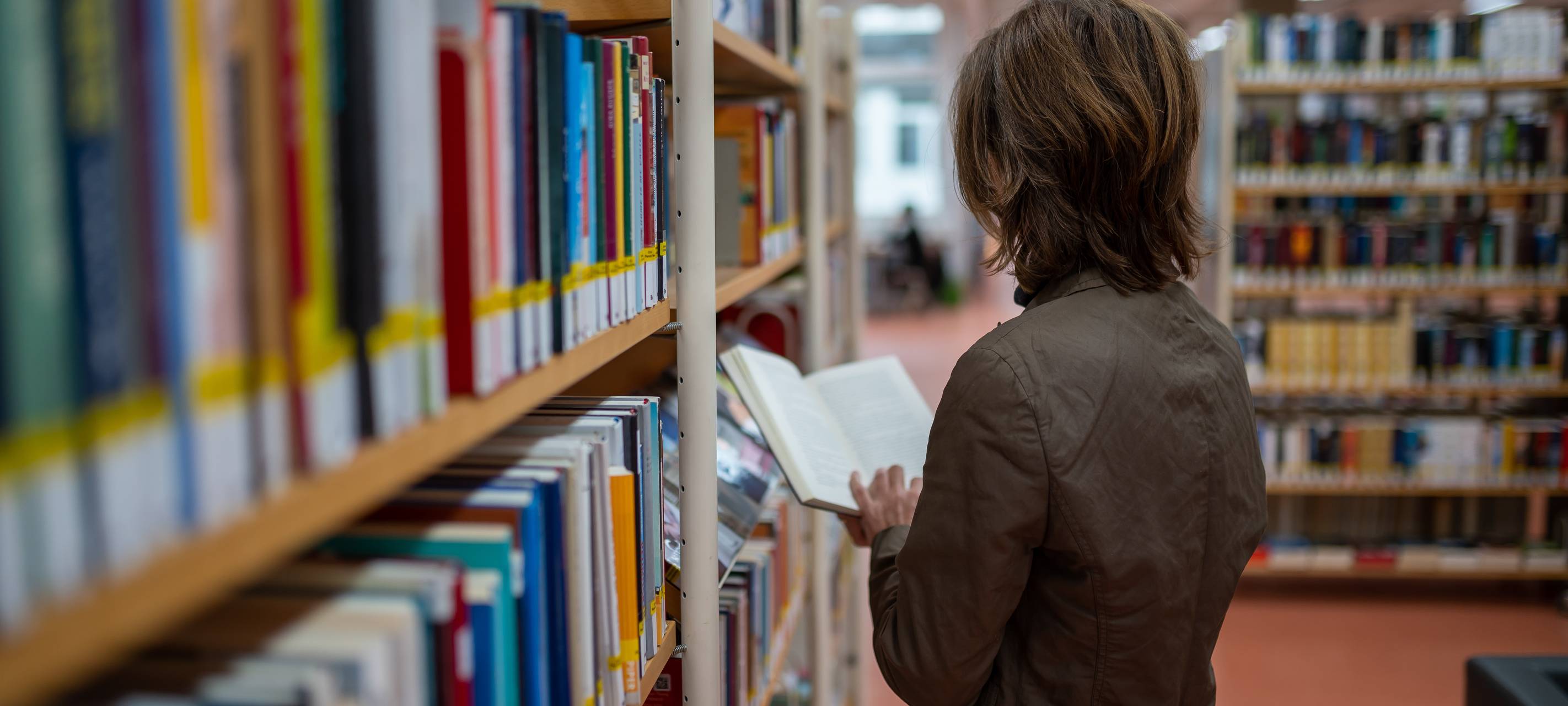 Eine Frau steht an einem Bücherregal
