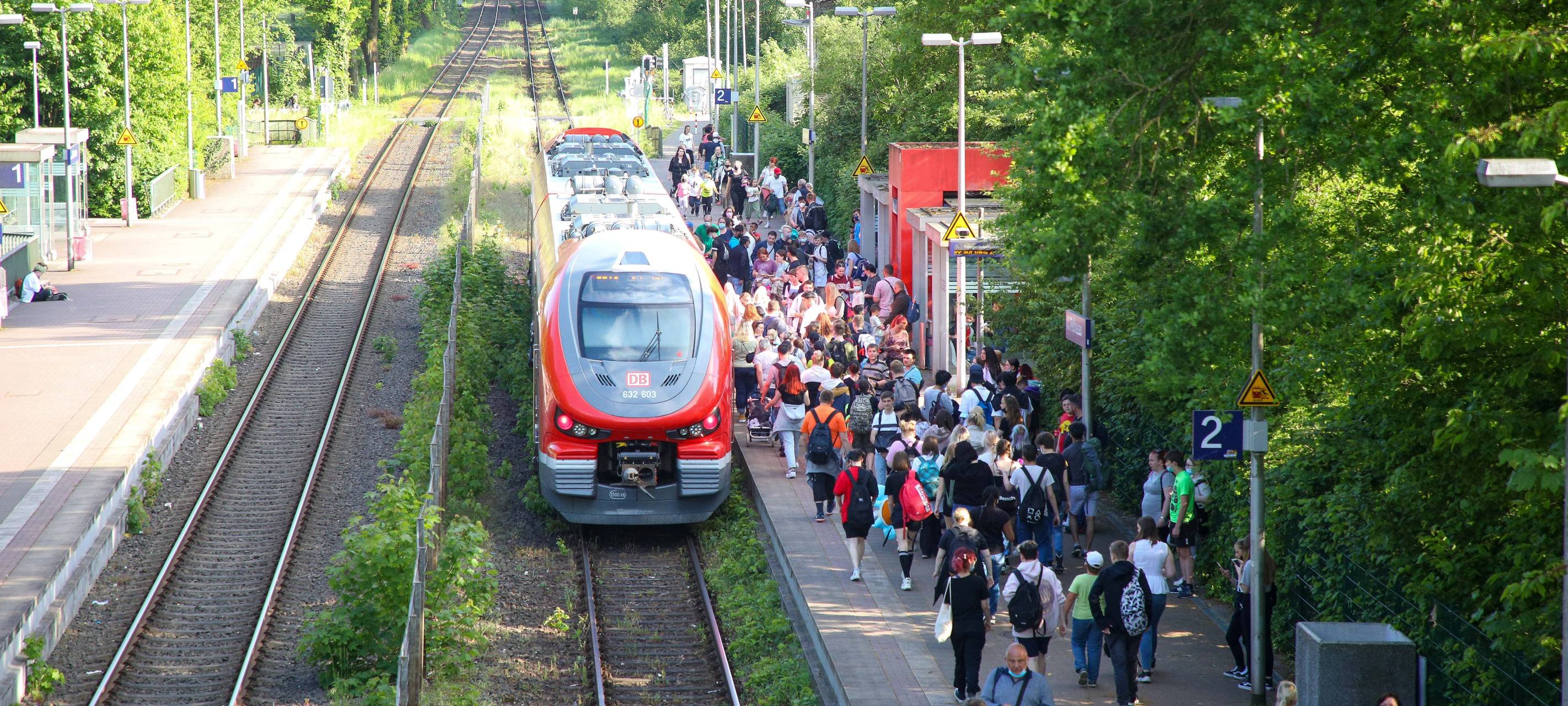 Voller Bahnsteig mit einfahrendem Zug