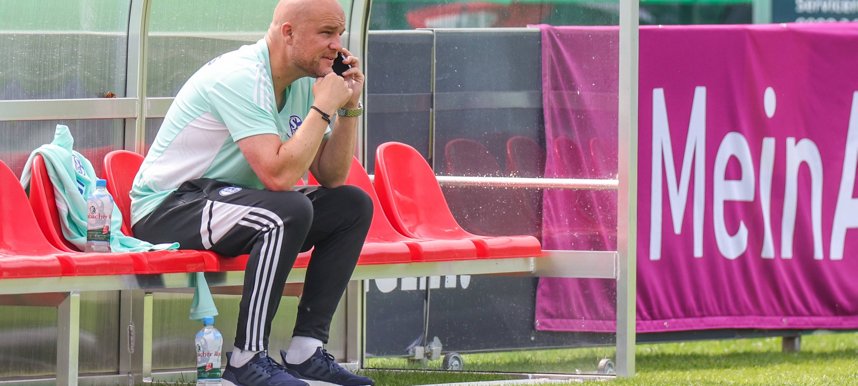 Schalke-Manager Rouven Schröder telefoniert am Rande des Trainingsplatzes
