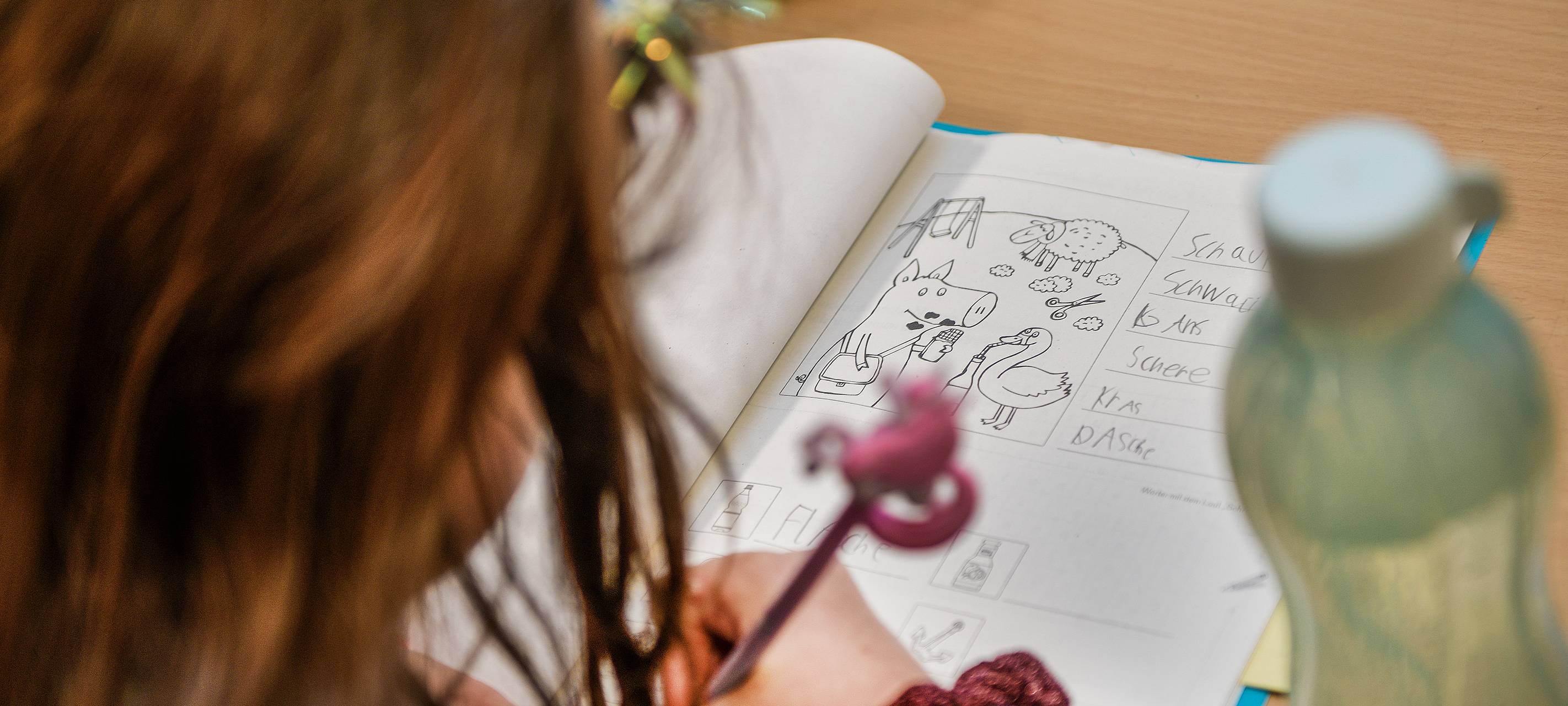 Eine Schülerin schreibt auf einem Arbeitsblatt