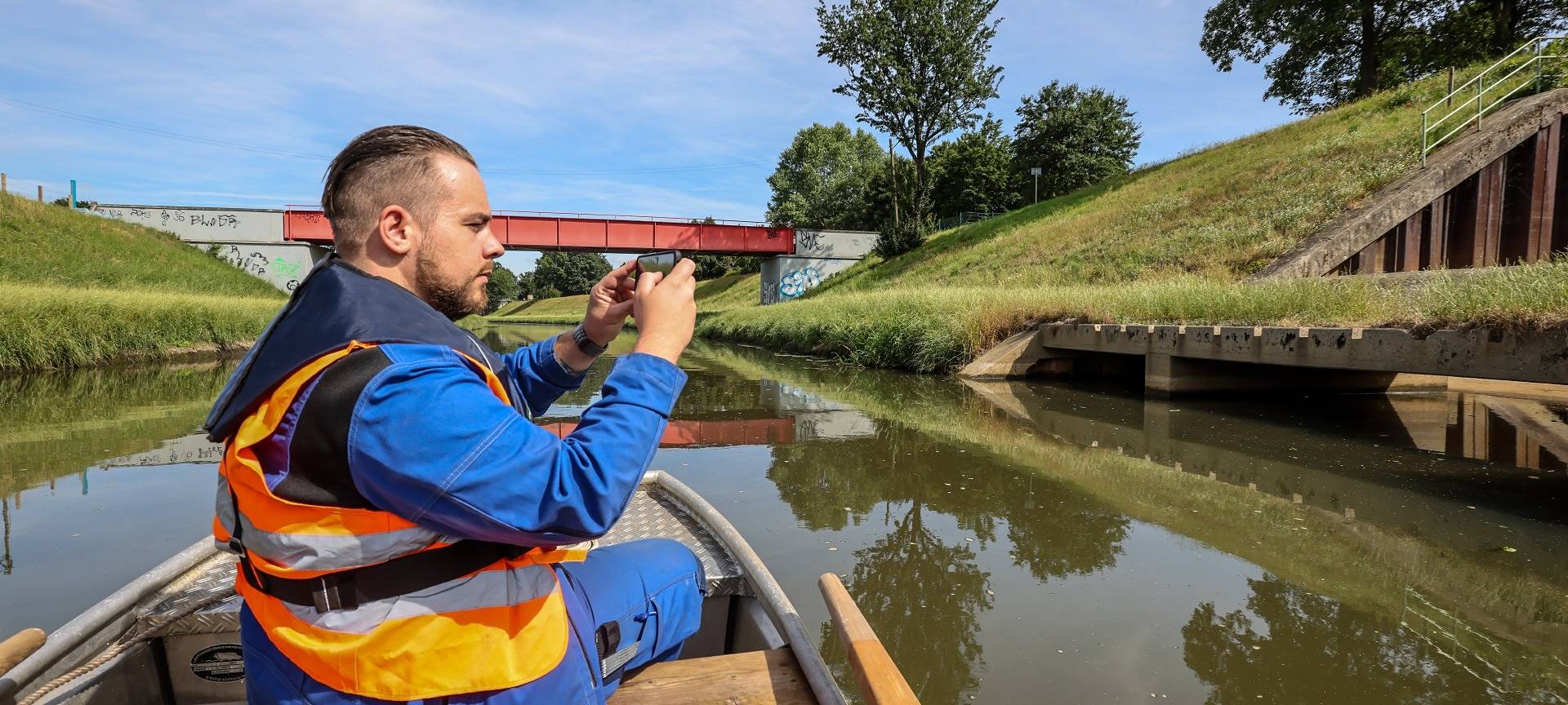 Ein Mitarbeiter der Emschergenossenschaft fährt in einem Boot auf der Emscher und macht Fotos