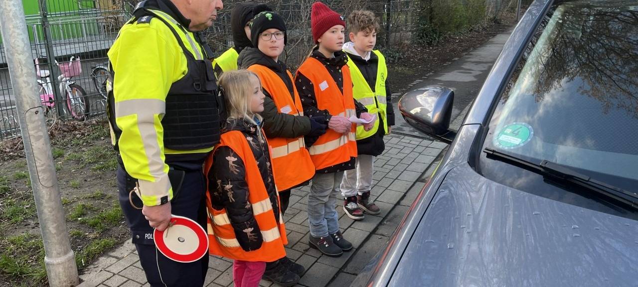 Ein Polizist und Schüler sprechen Autofahrer an