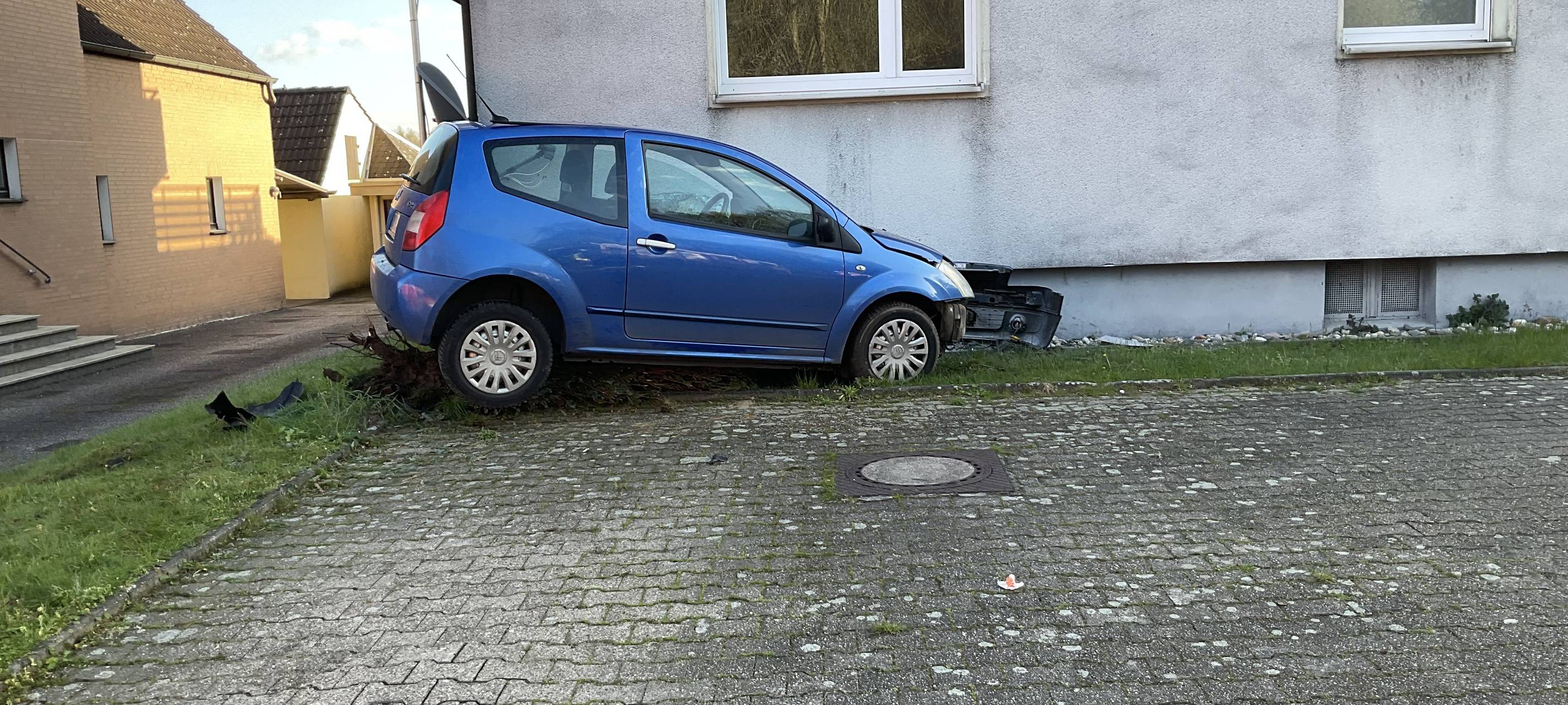 Ein blaues Auto an einer Hausfassade