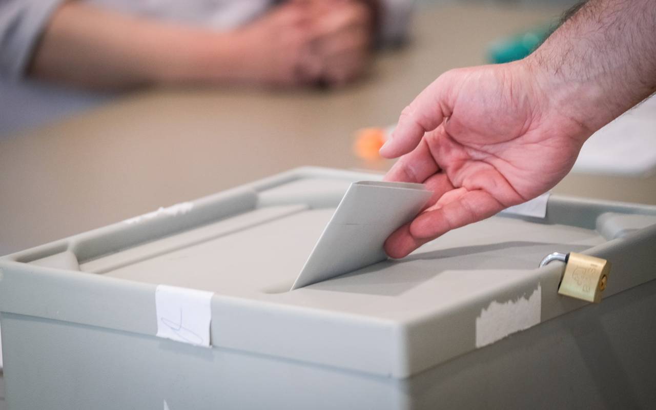 Wahlzettel wird in eine Wahlurne geworfen