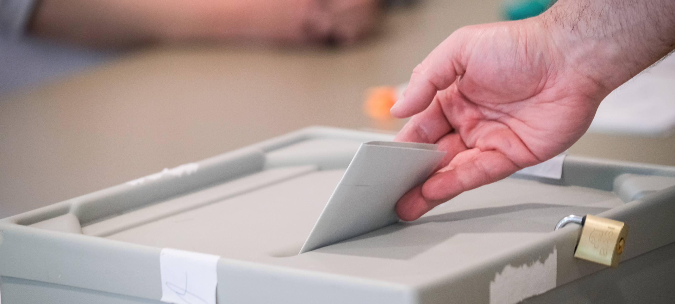 Wahlzettel wird in eine Wahlurne geworfen