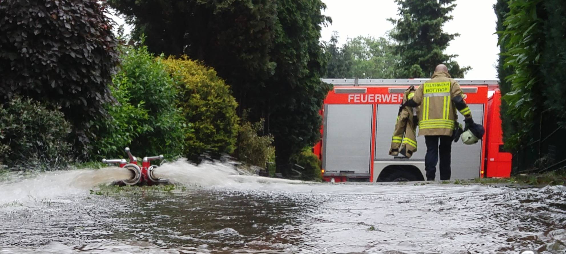 Ein Feuerwehrmann steht auf einer überfluteten Straße