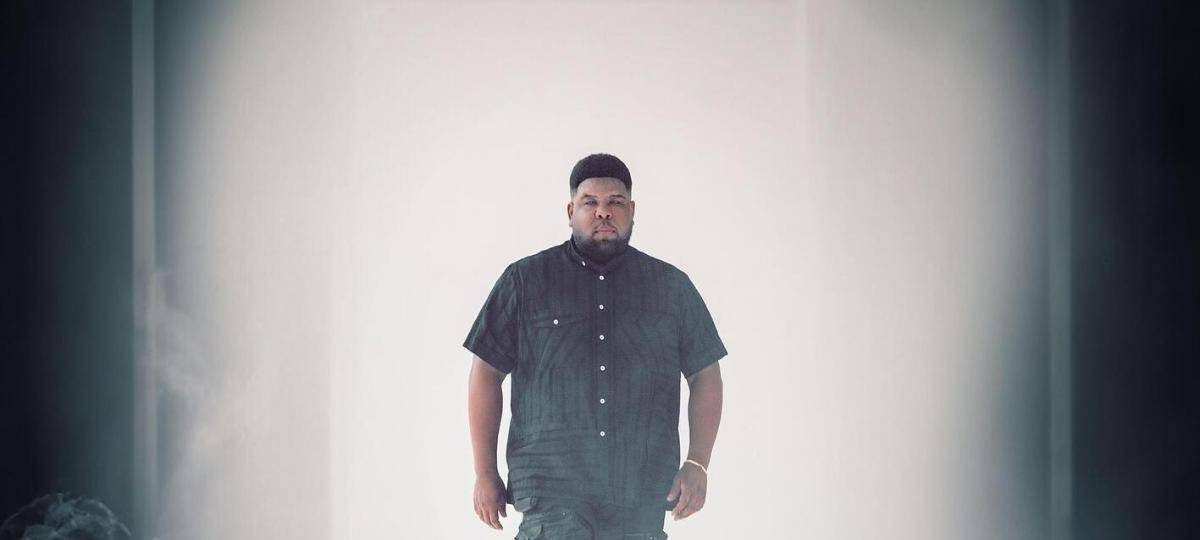 Das Musikcover der Single "Thee Unknown" von Ray Dalton zeigt ihn Barfuß in schwarzer Kleidung in einem weißen Raum mit Rauch.