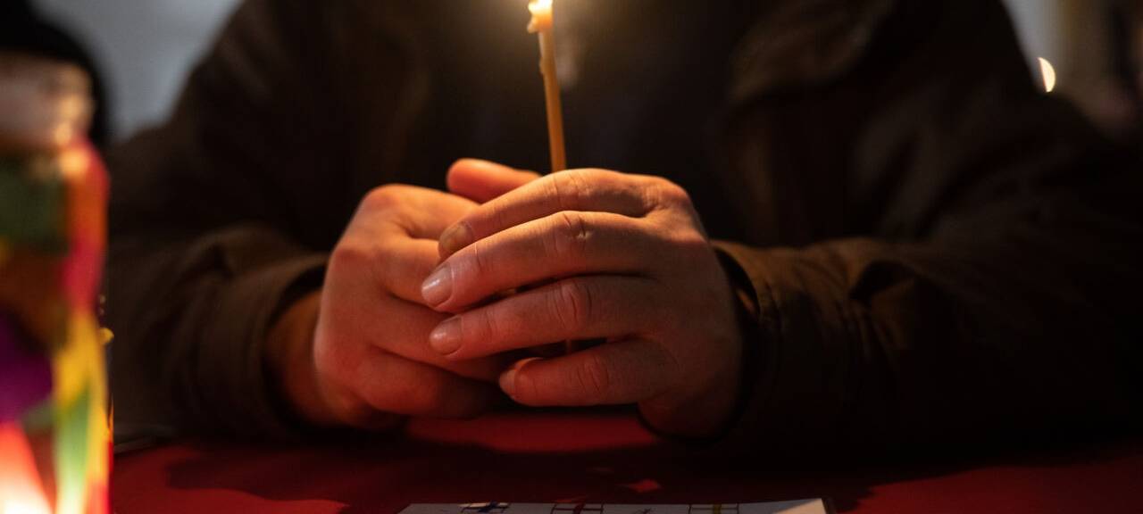 Besucher sitzt in der Weißfrauen Diakoniekirche mit einer Kerze beim Gottesdienst an einem Tisch. Die Kirche im Bahnhofsviertel öffnet bei der Veranstaltung am Heiligen Abend ihre Türen und schließt sie erst am ersten Weihnachtsfeiertag wieder. Das Angebot mit Gottesdienst, Weihnachtsessen, Musik und Übernachtungsmöglichkeit richtet sich an alle Menschen im Bahnhofsviertel. Hauptsächlich sind die Besucher jedoch wohnungslos oder haben sehr geringe finanzielle Mittel zur Verfügung.